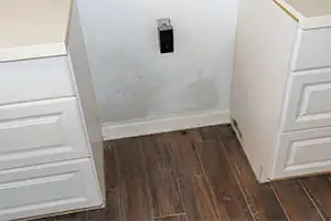 Taches d'humidité sur un mur entre 2 étagères, auréoles visibles.