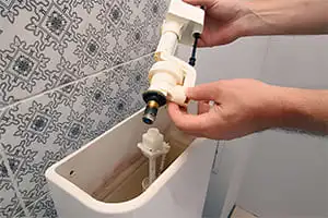 Réparation de fuite pour une chasse d'eau, vu sur le mécanisme de la chasse WC.
